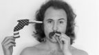 David Crosby poses with a gun, made from a folded-up American flag